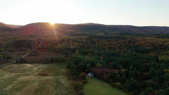 Sunrise along Cape Clear, Cape Breton. Autumn Fall Foliage aerial top view.  Cabot Trail. Mixed forest, deciduous trees with orange and yellow leaves. Fall colors. Cape Breton, Nova Scotia, Canada 