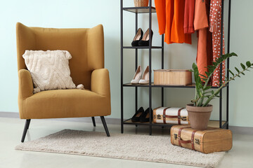 Rack with orange clothes near white wall in room
