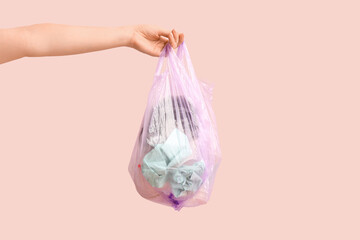 Woman with full garbage bag on pink background