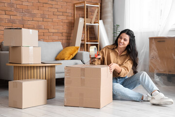 Beautiful woman taping box in room on moving day