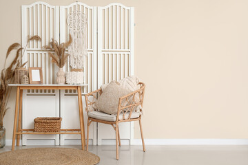 Armchair, table and folding screen near beige wall
