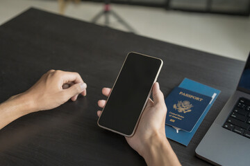 Hand Man Online booking and buying plane tickets using laptop phone and credit card Planning trip travel vacation with passport and ticket.