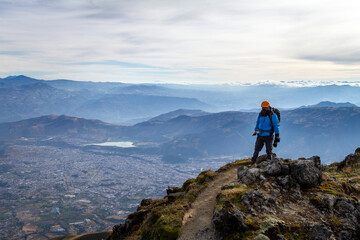 Turista en la cima del cerro imbabura de fondo la ciudad de Ibarra y laguna Yahuarcocha rodeado de montañas