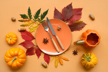 Beautiful table setting with fresh pumpkins, acorns, star anise and autumn leaves on orange background
