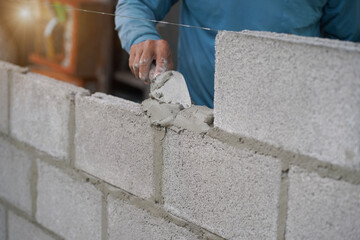 masonry worker make concrete wall by cement block and plaster at construction site