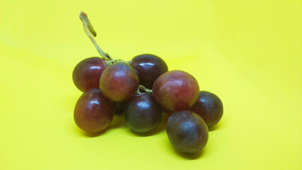 a sprig of purple grapes isolated on a yellow background