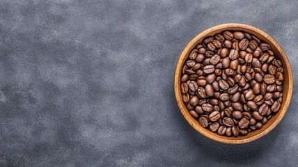 Brown coffee beans in wooden bowl on grey rustic background.