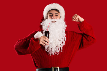 Young Santa Claus with cola on red background