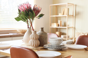 Table setting with vases and protea flowers in dining room
