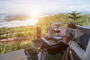 Coffee drift Coffee drips softly at sunrise on a wooden table with a backdrop of natural mountains and additional equipment.