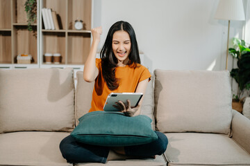 Obraz premium Asian woman using the smartphone and tablet on the sofa at home.