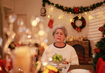 Sad and lonely old woman on Christmas Day at the dining table