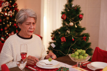 An old woman misses her family and is unhappy, sitting alone crying on Christmas Eve.