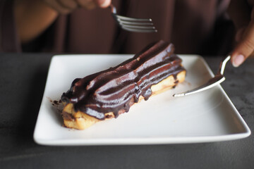 A Decadent Chocolate Eclair Placed Elegantly on a Plate, All Set and Ready to Enjoy
