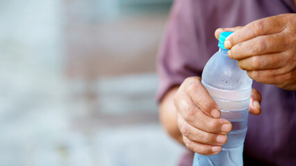 person opening cold water bottle with focus on hands, conveying refreshment and hydration. background is blurred, emphasizing action