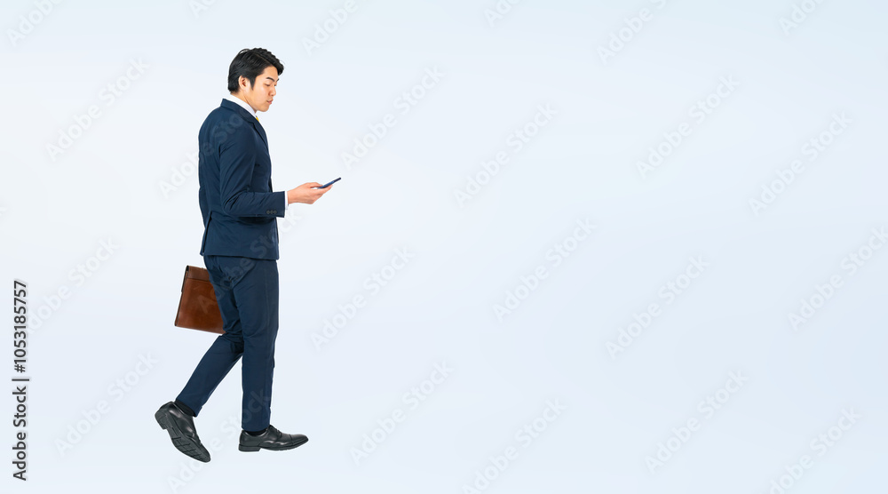 Aufkleber スマホを見ながら歩く若い男性ビジネスパーソンの全身写真（切り抜き背景透過pngも販売しております。作成者リンクから「png」で検索してください）
