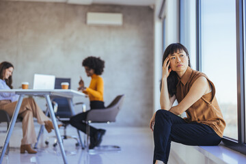 Fototapeta premium Thoughtful Woman in Modern Office Environment with Colleagues