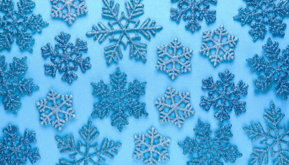 キラキラしたグリッターの青色の雪の結晶の背景