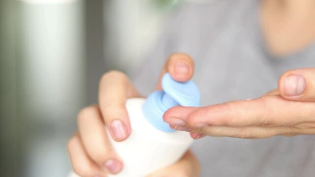 Close up of female hands appalling creme moisturizer on her hands. Blurry background 
