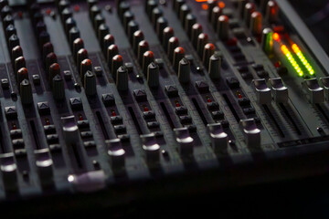 Obraz premium Close-up of an Audio Mixing Console with Faders and Knobs in Low Light