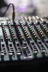 Close-up of an Audio Mixing Console with Faders and Knobs in Low Light