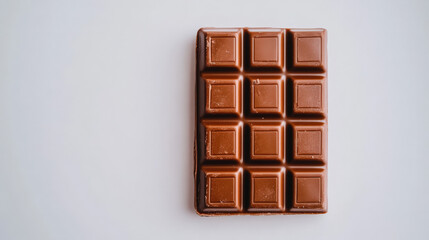 Obraz premium Chocolate Bar Minimalist: A single bar of milk chocolate rests on a white background, its smooth surface and squared design creating a minimalist and inviting visual.