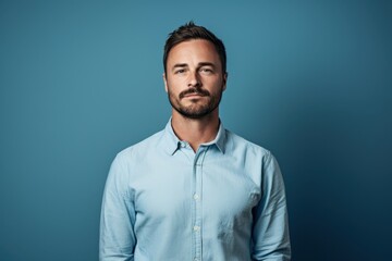 Fototapeta premium A man in a blue shirt is standing in front of a blue wall