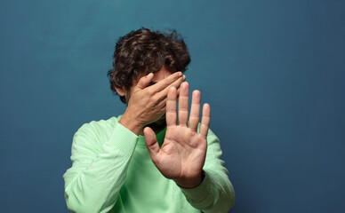 covering face with hand and putting other hand up front to stop camera, refusing photos or pictures