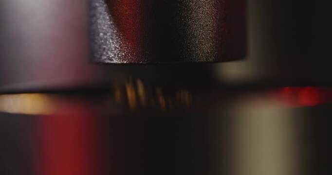 Macro, slow motion shot of coffee grounds coming out of an esthetic, professional coffee grinder in dramatic studio light