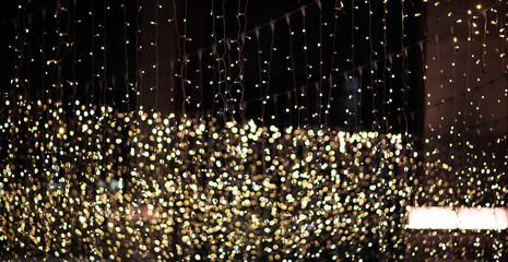 a close-up view of numerous strands of twinkling yellow fairy lights against a dark background,...