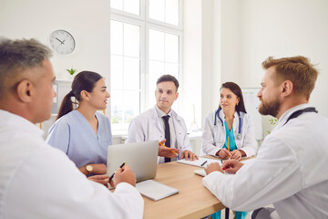 Confident doctor meeting, surgeons, nurse staff in white medic uniform talking to colleagues at...