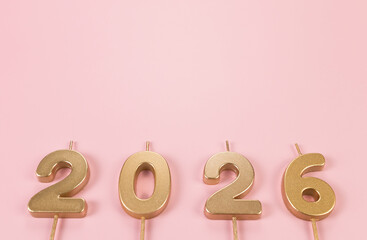 2026 Happy New Year. Top view of gold numbers on pink background. Copy space, flat lay.