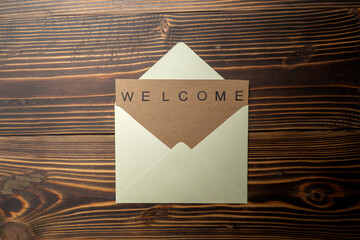 Top view of envelope and postcard with brown card with words Welcome on it. Welcome greeting for...