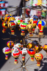 A vibrant collection of colorful hot air balloons suspended from a pole in souvenir shop