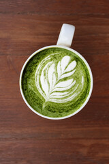 A cup of green tea matcha latte on wooden background                                                                                                                                                    