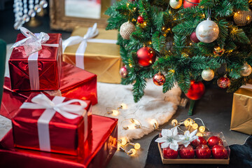 Gifts under Christmas tree with red, gold and silver toys. Festively decorated Christmas tree with garlands. Symbol of the new year in traditional colors