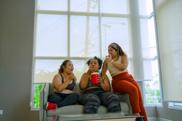 Plus size women eat popcorn at fitness center.