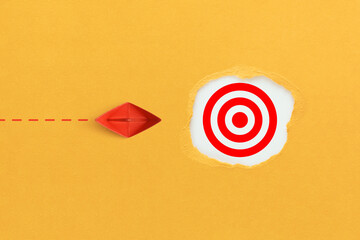 Target concept with red paper ship. Hole in the yellow paper with torn sides and target icon