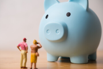 Senior couple tourist and blue piggy bank on wooden table white wall background. Money financial management, pension, savings planning, deposit account for elder or retirees, aging society concept