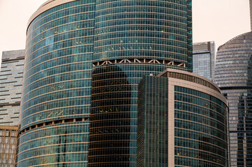Fototapeta premium Skyscrapers in business district against blue sky. Looking Up high-rise office buildings. Evening time, sunset. Orange, yellow and gold shades of color. Angled view.