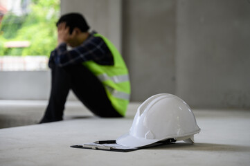 Young Asian male construction worker staff feeling sad and upset while sitting on the floor of the...