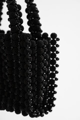 Black and white photo of a minimalist style beaded bag illuminated with contrasting shadow bands. Abstract and stylish look, suitable for fashion magazines, advertisements.