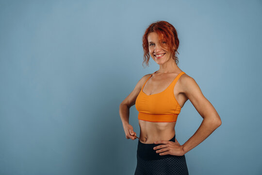 Fototapeta In yellow top, sportive clothes. Woman is in the studio against background