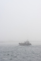 The barge floats on the river in the fog. Water transport by barge. Crossing the river. Transport infrastructure in remote regions of Siberia and the Russian Far East. Foggy weather. Poor visibility.