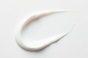 A wide short smear of white cream on a smooth white surface, top view.
