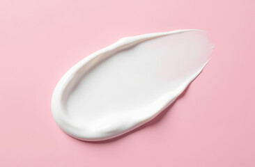 A smear of thick white cream on a solid pink background, top view.