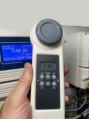 Digital water tester provides accurate readings of crystal clear water with beige tiled floor,...