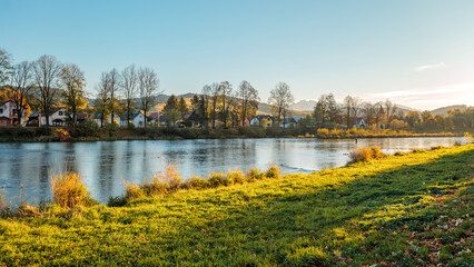 Fototapeta premium The grassy bank of the Dunajec River. Beautiful autumn. Golden hour. View towards the Tatra Mountains. Sromowce Niżne. View towards Slovakia.