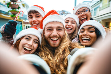 Happy friends wearing santa claus hat taking selfie at Christmas time together on city street - Group of young multi ethnic people having new year party outside - Winter holidays concept