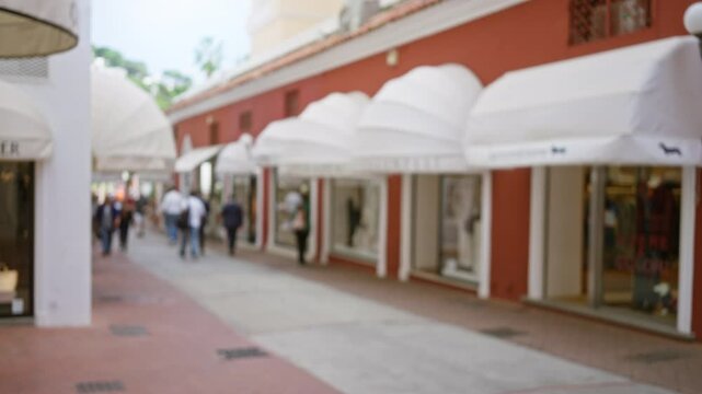 Defocused street view with blurred people strolling past luxury stores on a charming capri island walkway under white awnings, creating a dreamy and serene atmosphere.